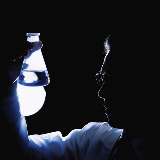 scientist looking at beeker filled with solution in his right hand
