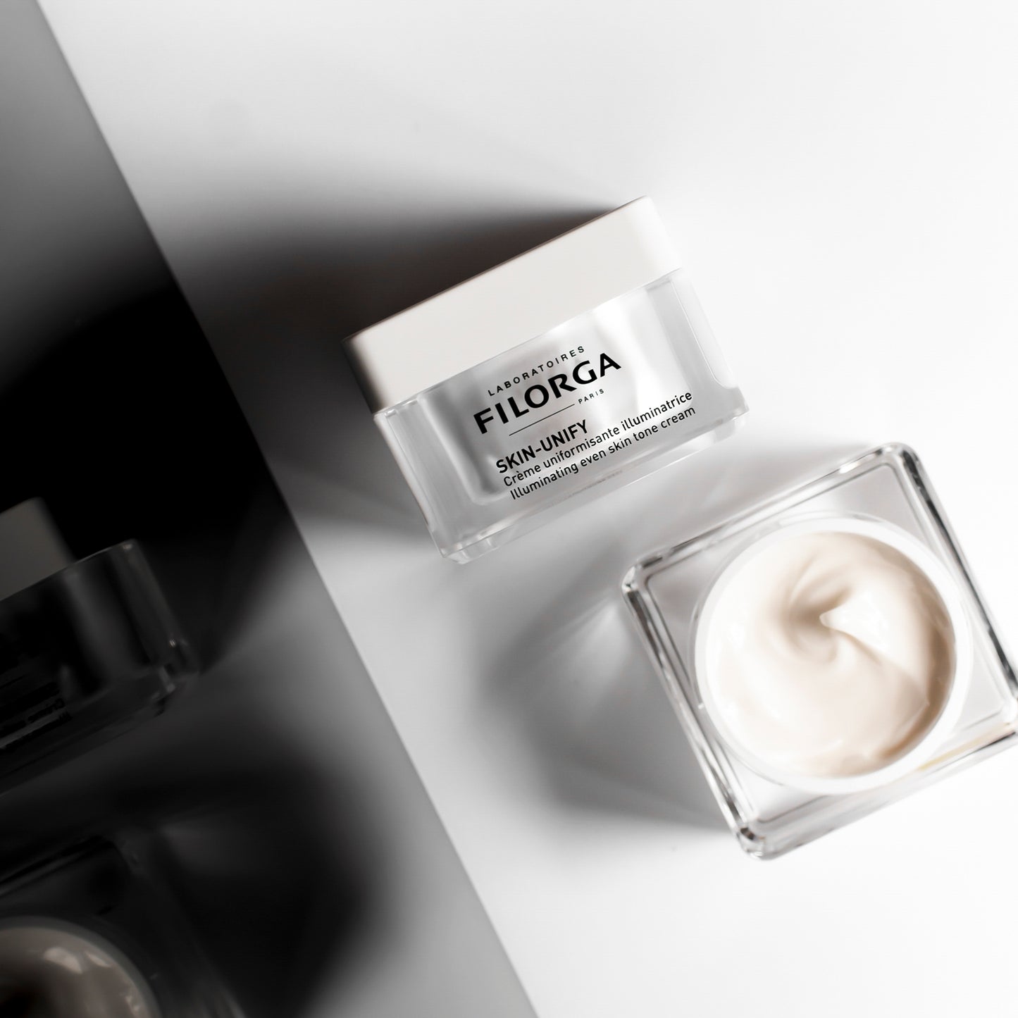 Closed jar on its side and open jar face up showing FILORGA SKIN-UNIFY cream