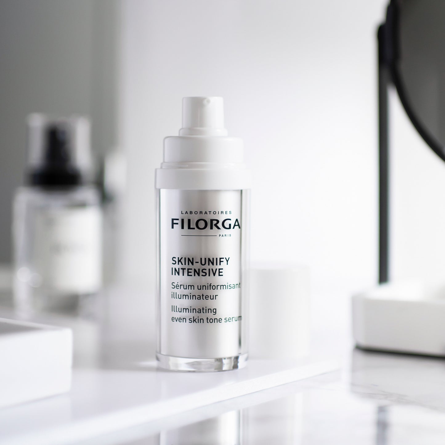 FILORGA SKIN-UNIFY INTENSIVE open bottle on a white marble vanity with a mirror