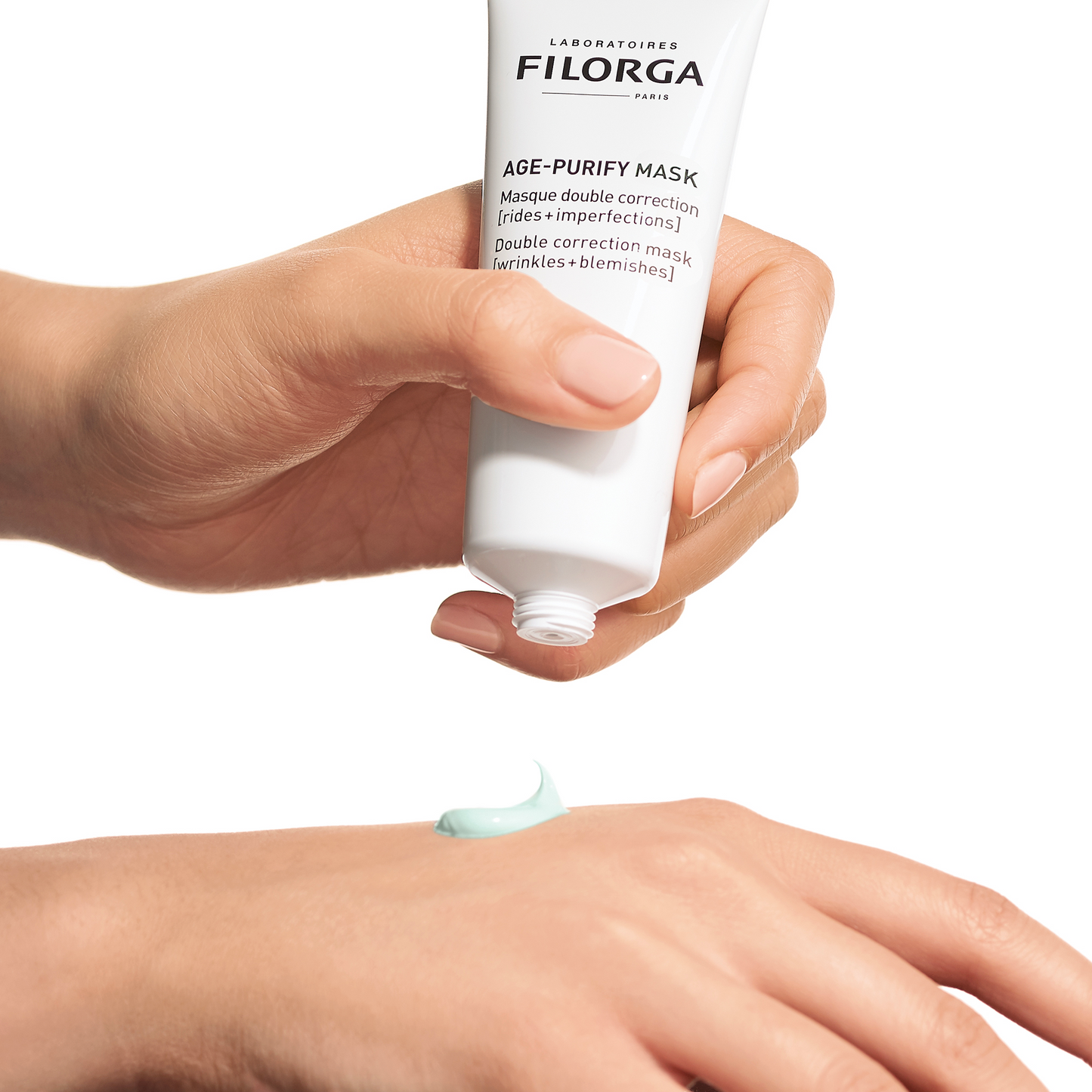 FILORGA AGE-PURIFY MASK tube dispensing green cream mask onto top of hand