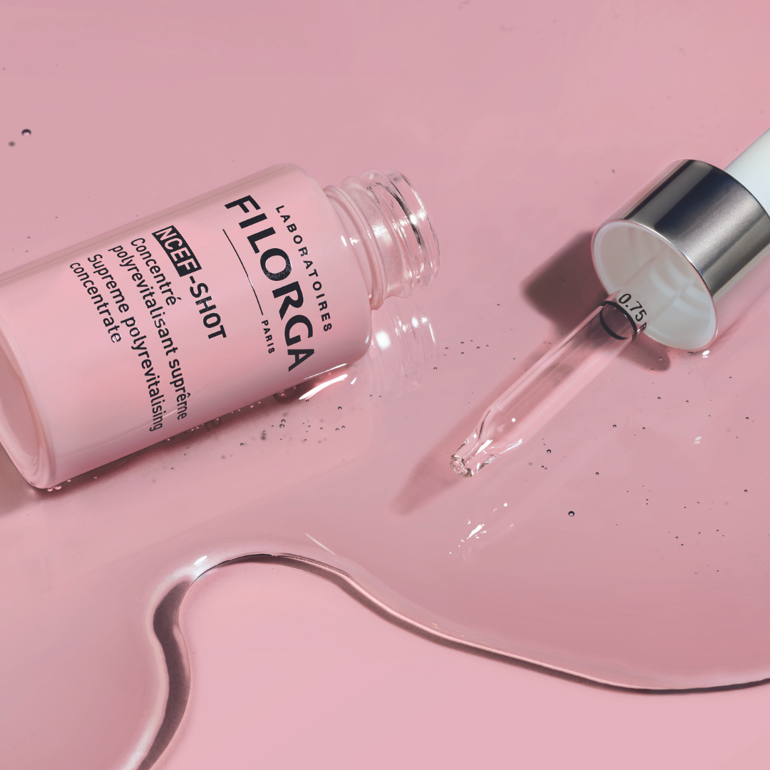 FILORGA NCEF-SHOT 15ml bottle open on its side with dropper on pink background of serum